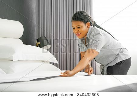 African Maid Making Bed In Hotel Room. Staff Maid Making Bed. African Housekeeper Making Bed.