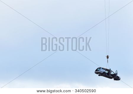 Discarded Old Car Without Wheels, Lifted Up By Cables Against A Sky Before Recycling, With Text Spac