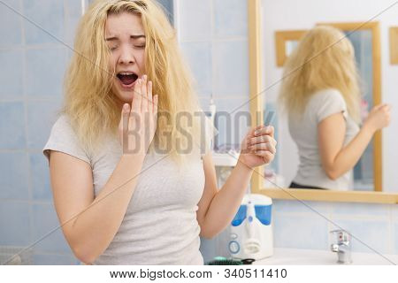 Young Blonde Female Feeling Dull And Tired After Waking Up. Woman Yawning Being Sleepy In Bathroom.