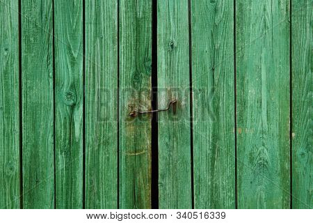 Iron latch and green wooden gate closeup on the ranch house for background or texture