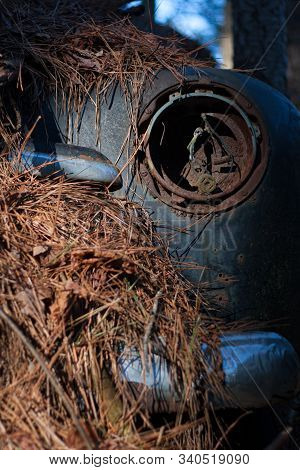 An Old Rusted Auto Headlight Socket On A Car Covered In Pine Straw.