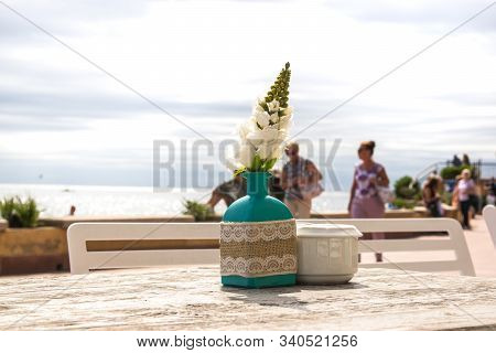 Warehouse On The Open Air With People. Chairs And Tables Outside On The Summer Sun Weather. Vase Wit