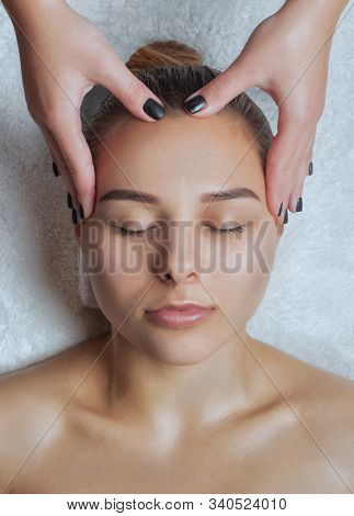 Masseur Makes A Relaxing Massage On The Face, Neck, Shoulders And Collarbones Of A Young Beautiful W