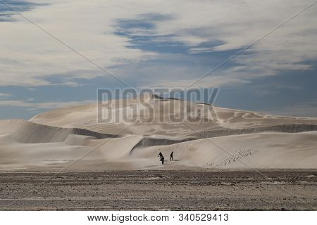 People Walking Up A Desert-like Sand Dune
