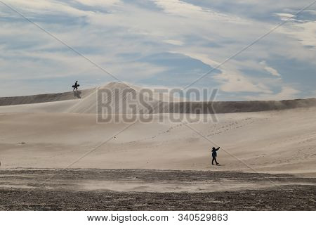 People Walking Up A Desert-like Sand Dune