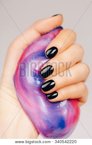 Hands With Black Manicure Holding Slime In Blue And Pink Vibrant Colors