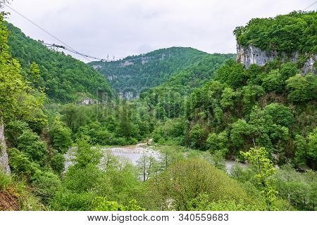 A Gorge In The Mountains With A Suspension Bridge Over It. Skybridge Suspension Bridge Over A Precip