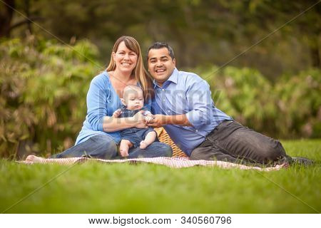 Happy Mixed Race Family Having a Picnic and Playing In The Park.