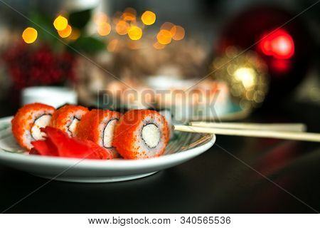 California Rolls And Sushi Poppies On Christmas Table With Ginger And Sticks