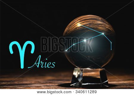 Crystal Ball With Constellation Near Aries Zodiac Sign On Wooden Table Isolated On Black