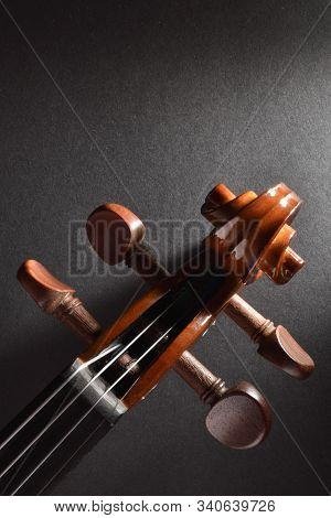 Violin Pegbox And Bow On Black Textured Table Top View. Vertical Composition.