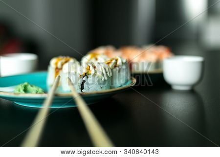 Cream Rolls With Soy Sauce Ginger And Wasabi On A Black Table And Blue Plates With Chopsticks
