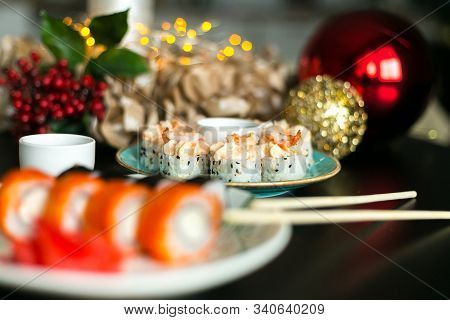 California Rolls And Sushi Poppies On Christmas Table With Ginger And Sticks