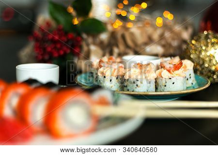California Rolls And Sushi Poppies On Christmas Table With Ginger And Sticks