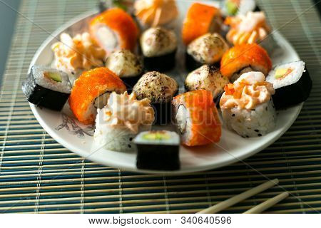 Set Of California Rolls, Butter Cream, Shrimp On A White Platter And A Black Table. With Ginger Soy 