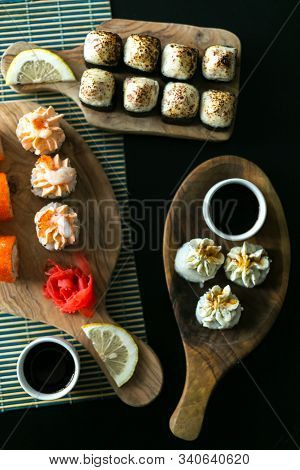 A Set Of California Rolls,some Cream Cheese, Shrimp On Wooden Platters And The Black Table. With Gin