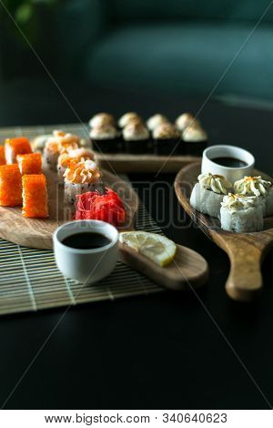 A Set Of California Rolls,some Cream Cheese, Shrimp On Wooden Platters And The Black Table. With Gin