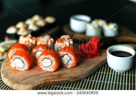 A Set Of California Rolls,some Cream Cheese, Shrimp On Wooden Platters And The Black Table. With Gin