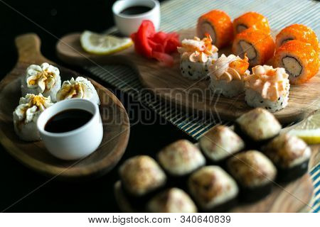 A Set Of California Rolls,some Cream Cheese, Shrimp On Wooden Platters And The Black Table. With Gin
