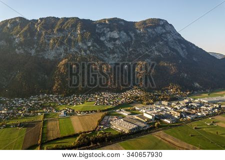 Aerial View Of Green Meadows With Villages And Forest In Austrian Alps Mountains.
