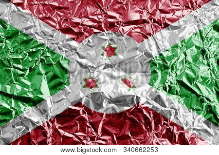 Burundi Flag Depicted In Paint Colors On Shiny Crumpled Aluminium Foil Closeup. Textured Banner On R