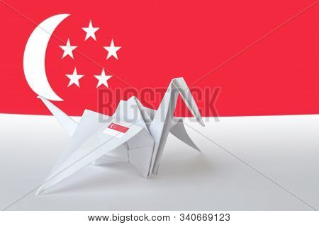 Singapore Flag Depicted On Paper Origami Crane Wing. Handmade Arts Concept