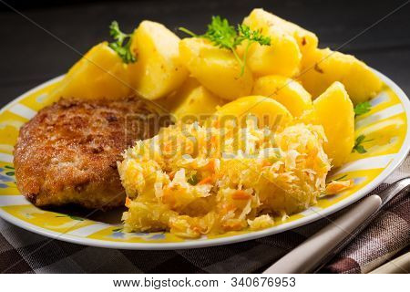 Minced Pork Cutlet Served With Potatoes And Sauerkraut Salad.