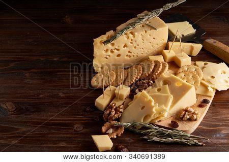 Pieces Of Cheese, Nuts, Raisins, Snacks For Wine On A Wooden Background. Appetitive Copy Space