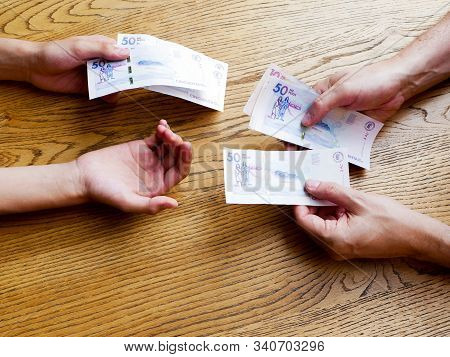 Hands Of A Man Giving Fifthy Thousand Pesos Bills To A Young That Is Asking For More Money Over A Ta