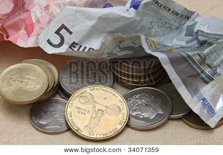 Arrugado de billetes son empujadas a un lado para dar paso a un retorno de monedas de dracmas griegas.