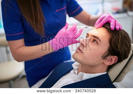 Male having aestetic intervention on his forhend in beauty salon