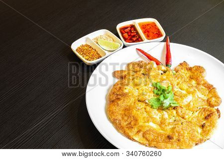 Thai-style Egg Omelette Isolated, And Served In A White Plate With Chilli Padi.