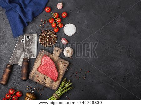 Slice Of Raw Beef Sirlion Steak On Wooden Chopping Board With Tomatoes,garlic And Asparagus Tips And