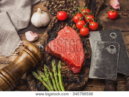 Slice Of Raw Beef Sirlion Steak On Wooden Chopping Board With Tomatoes,garlic And Asparagus Tips And