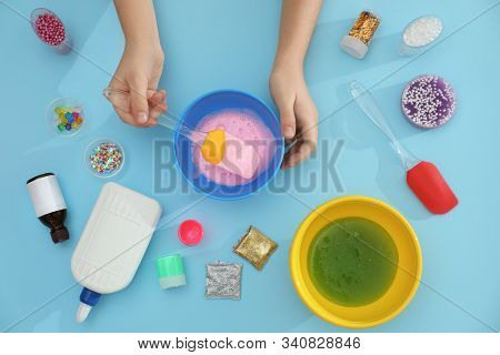 Little Girl Making Slime Toy On Light Blue Background, Top View