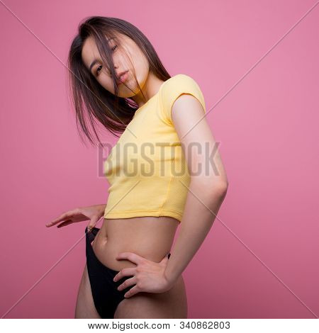 Beautiful Asian Woman Posing And Showing How Thin She Pulls Black Panties In F Yellow T-shirt On A P