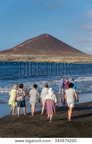 El Medano, Spain - July 9 2019: Senior Local Women Walking On Playa El Medano Beach During Sunrisee
