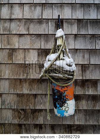 A Buoy With Roap And Topped With Snow Hangs From A Wall