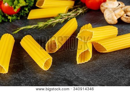 Dry Manicotti Pasta With Mushrooms And Tomato On Black Background.