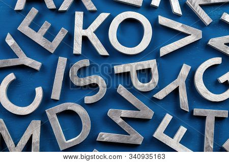 Abstract Flat Background Of Silver Metal English Alphabet Characters On Classic Blue Background.