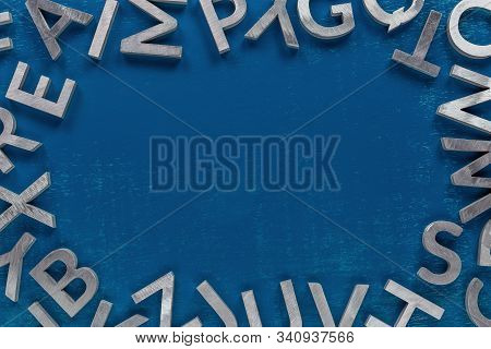 Frame Mockup Made Of Of Silver Metal English Alphabet Characters On Classic Blue Background.