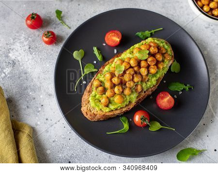 Rye Toast With Avocado, Roasted Chickpeas, Herbs On A Dark Plate. Plant-based Vegetarian Food. Gray 