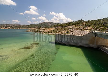 Dam Of The Gadoura Water Reservoir On Rhodes Island, Greece With  Blue And Turquoise Water  And Land