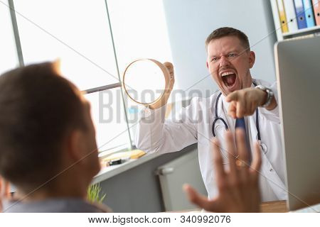 Angry Doctor Interrogates The Patient, Yelling At Him, Pointing To Man He Talking To And Holding Lam