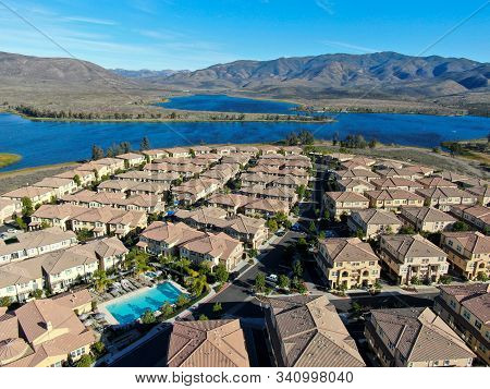 Aerial View Of Identical Residential Subdivision Condo With Big Lake And Mountain On The Background 