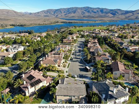 Aerial View Of Identical Residential Subdivision House With Big Lake And Mountain On The Background 