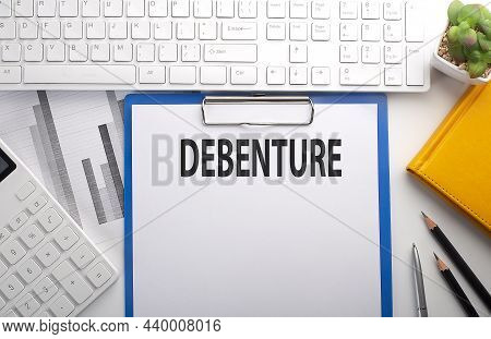 Debenture Written On The Paper With Keyboard, Chart, Calculator And Notebook