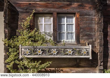 Wooden Flower Pot With Edelweiss Flower Carving Placed At The Window Of Old Swiss Chalet