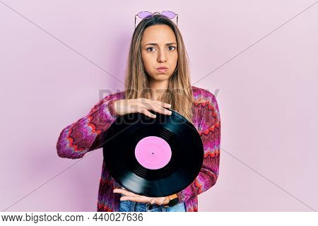 Beautiful hispanic woman wearing hippie style holding vinyl disc puffing cheeks with funny face. mouth inflated with air, catching air. 