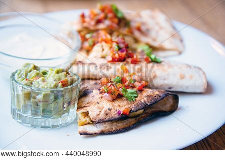 Delicious Mexican quesallidas made with chicken, tomato pieces and served with guacamole sauce.